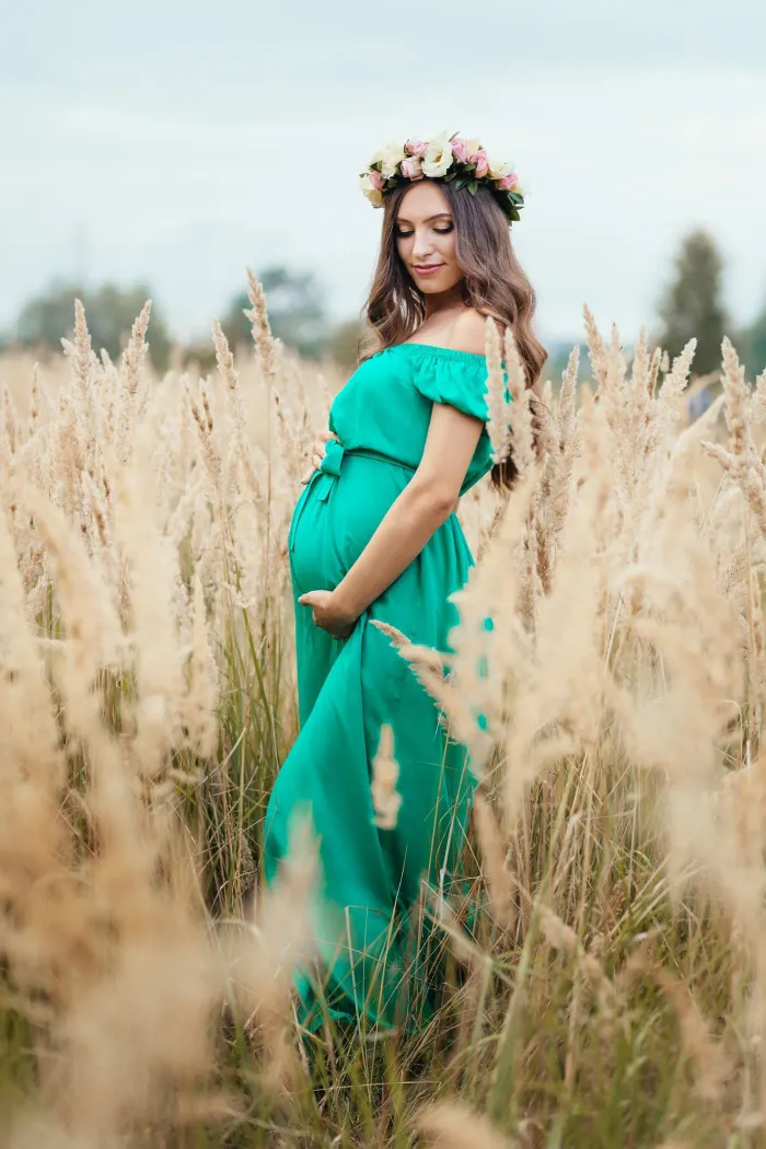 Expectant mother in a designer gown posed under soft studio lighting during a maternity shoot